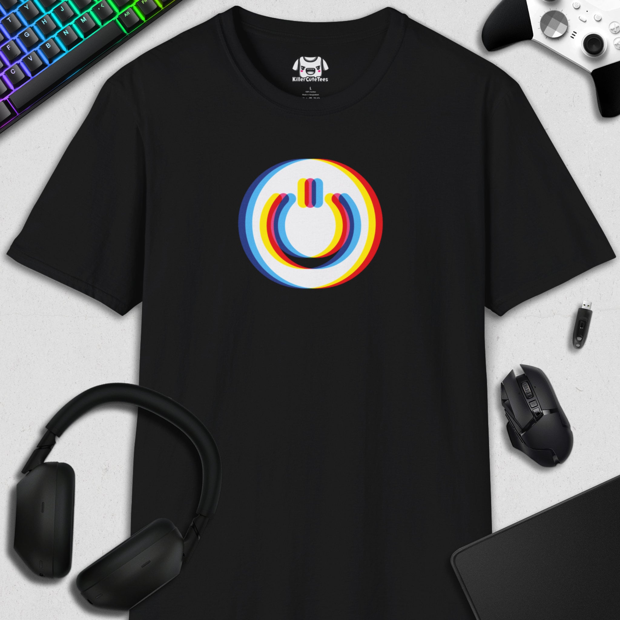 Black t-shirt with a colorful POWER BUTTON on a desk with gaming accessories.
