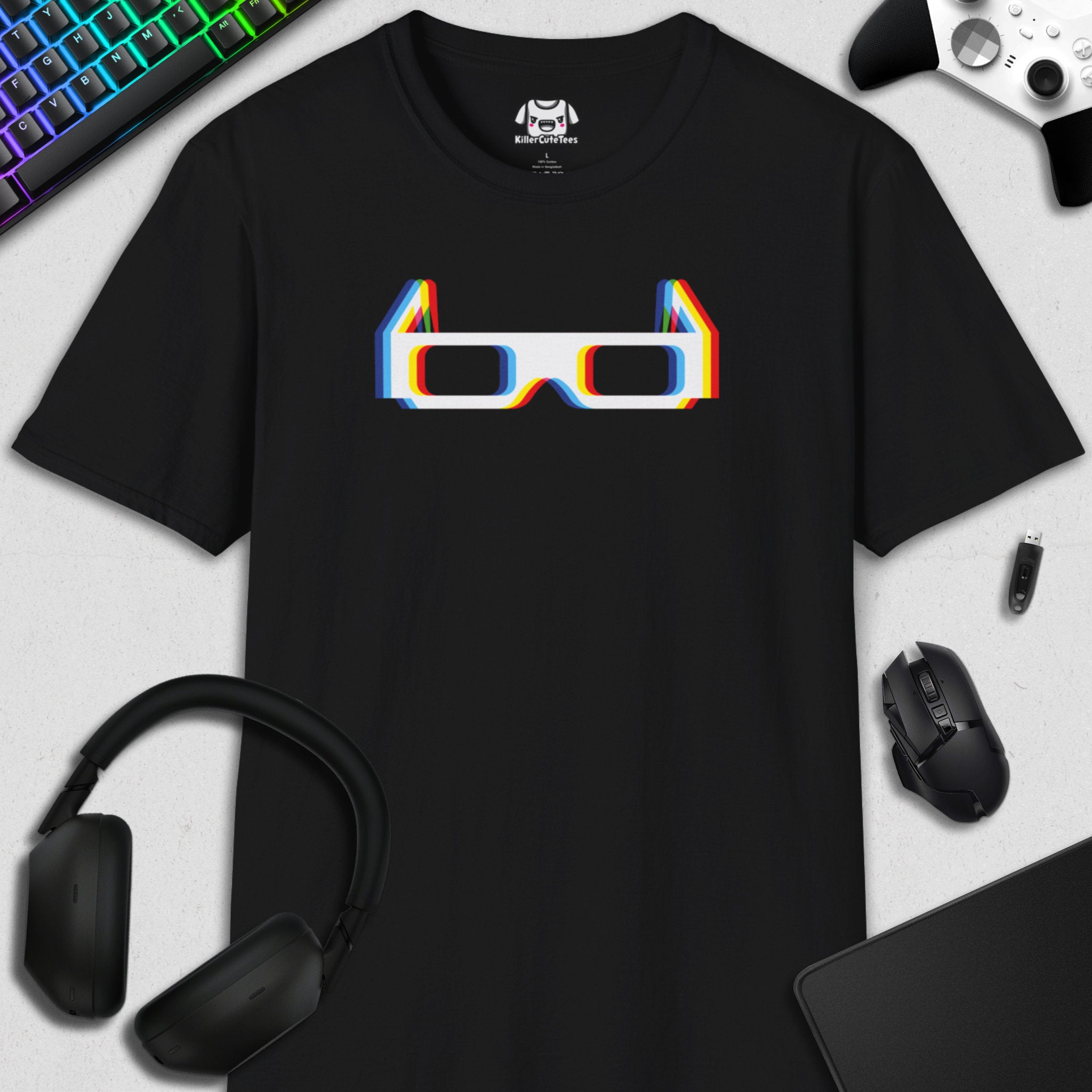 Black t-shirt with colorful 3D glasses graphic on a desk with gaming accessories.